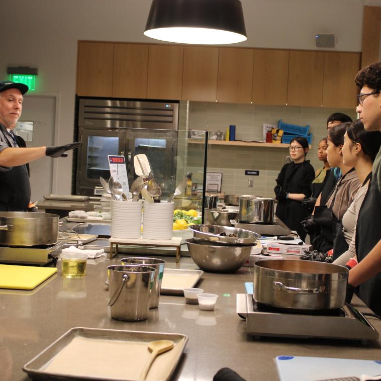Chef Lucio Palazzo engaging students with cooking techniques at Quaker Kitchen