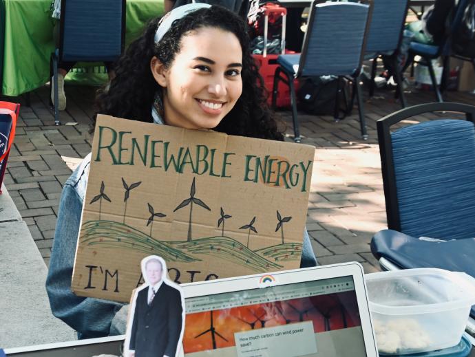 Student holding renewable energy sign