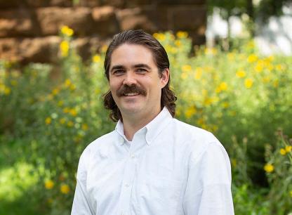 man in white shirt near yellow flowers